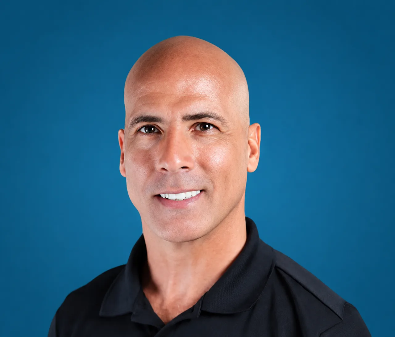 Male healthcare provider smiling, wearing black polo shirt