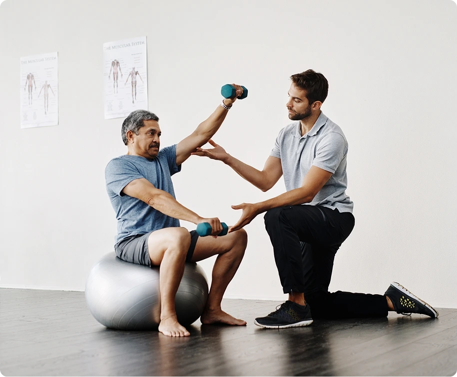 Physical therapist guiding patient performing dumbbell bicep curl on exercise ball