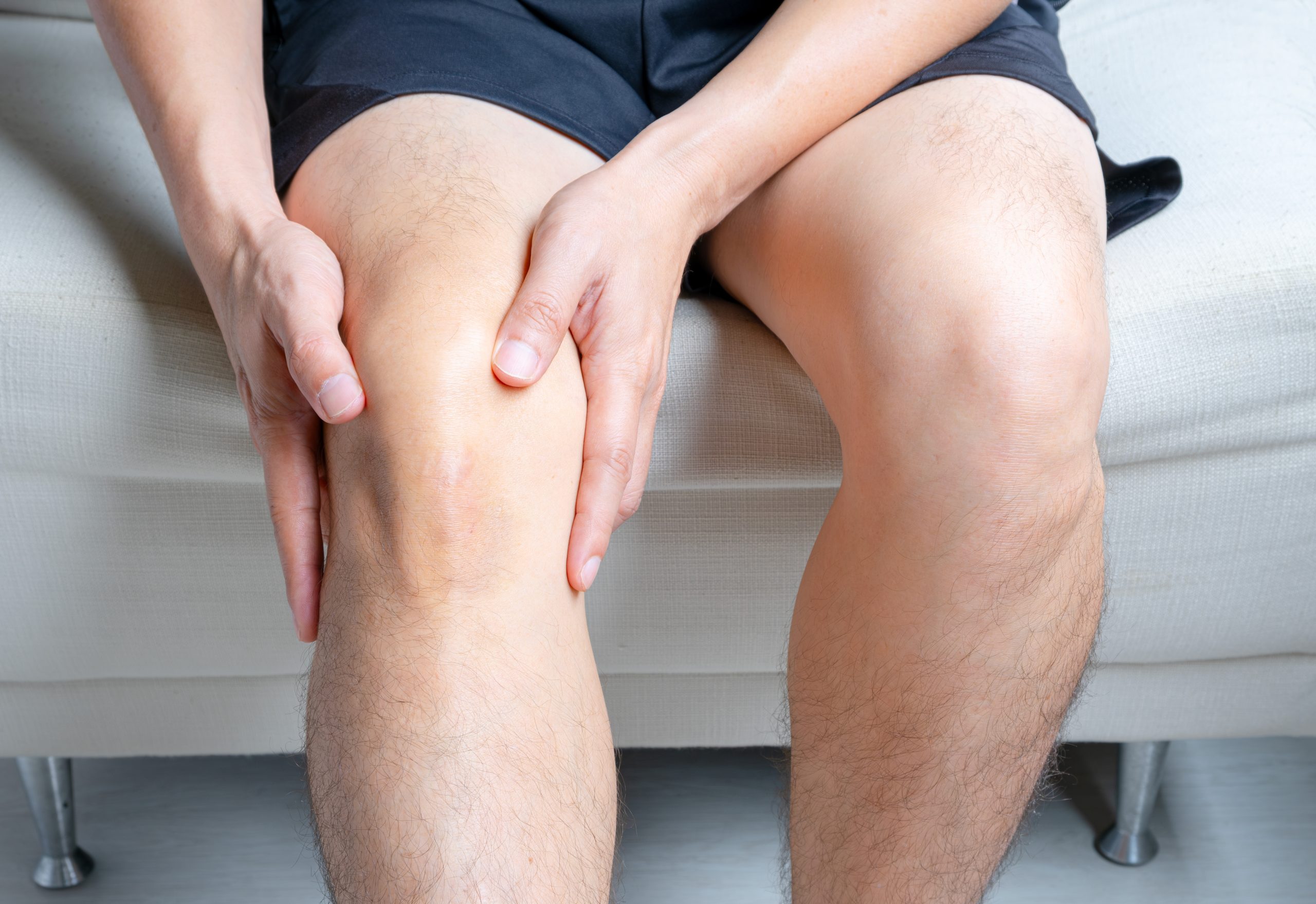 Person holding knee in pain while seated