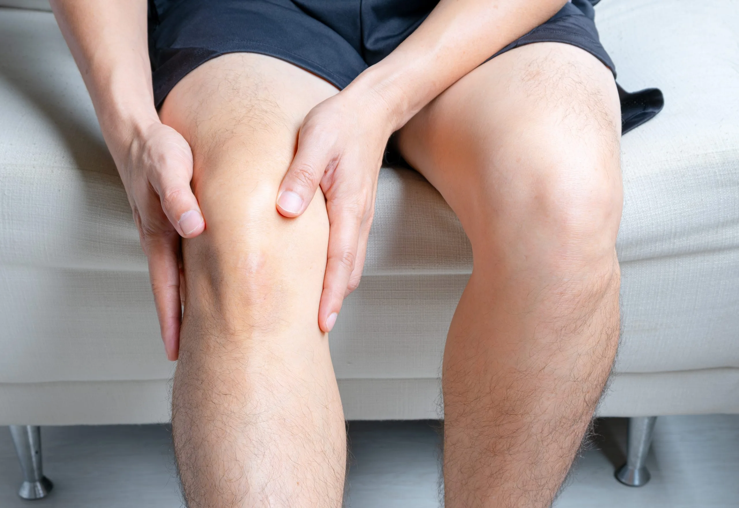 Person holding knee in pain while seated