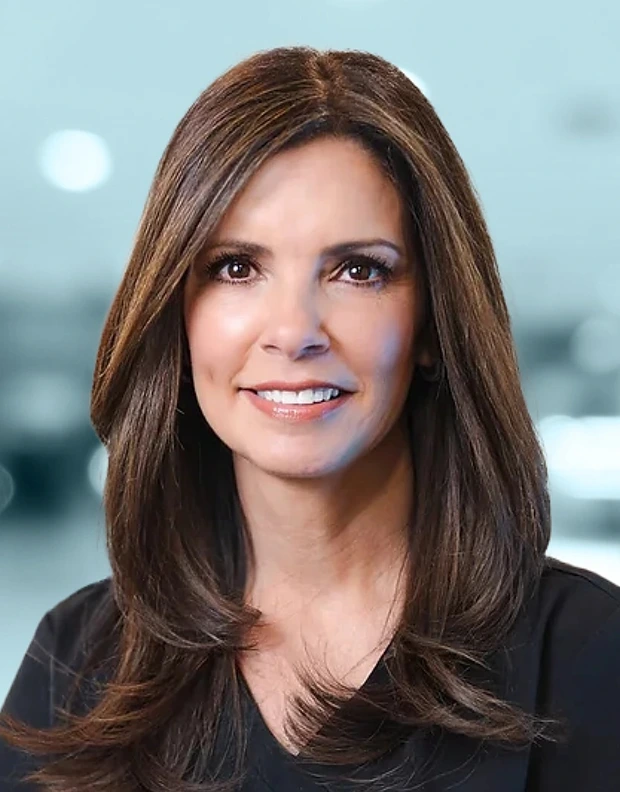 Professional headshot of woman with shoulder-length brown hair smiling, wearing black shirt