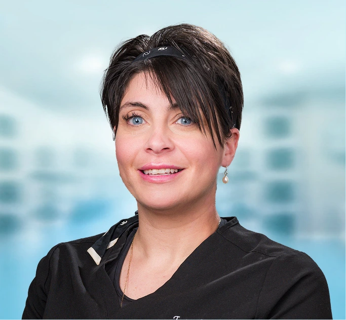 Woman with short dark hair smiling at camera against blurred office background