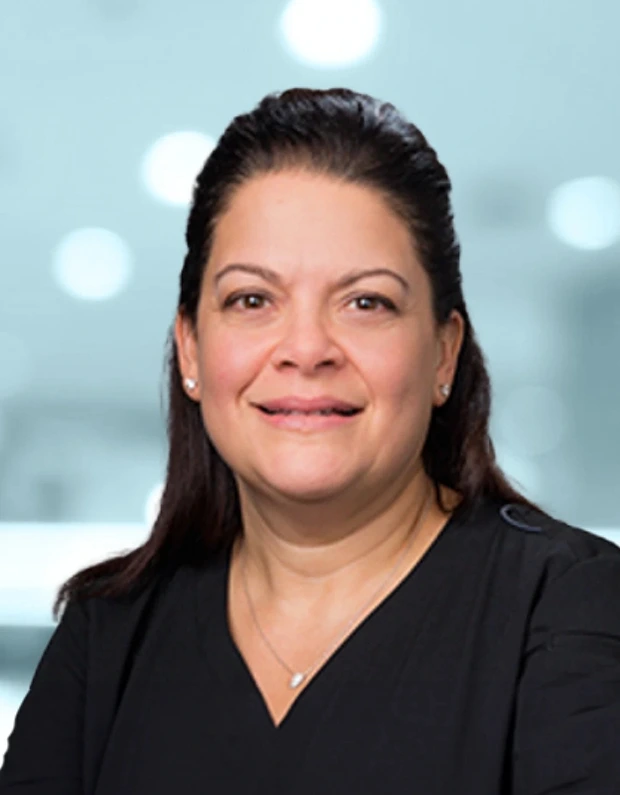 Professional headshot of woman with dark hair pulled back, wearing black v-neck top