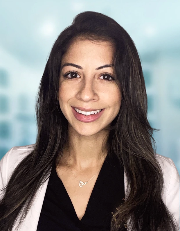 Professional headshot of woman with long black hair smiling, wearing black and white top