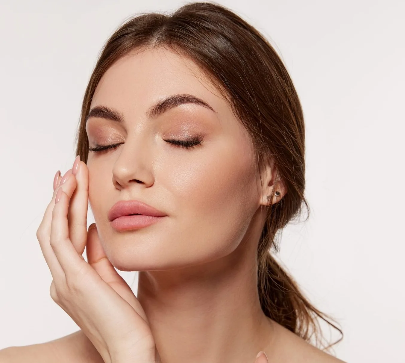 Woman in profile with eyes closed, hand touching her face against white background