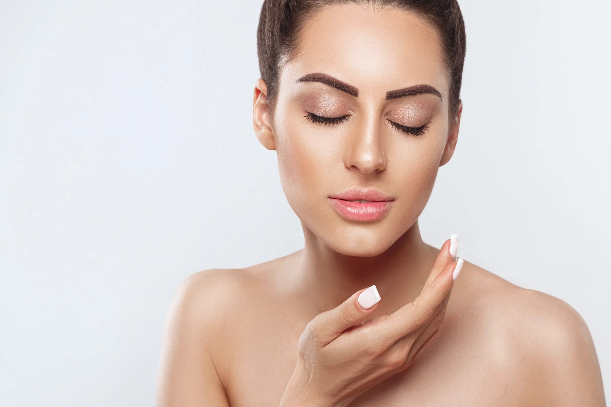 Woman with clear skin touching her cheek with eyes closed