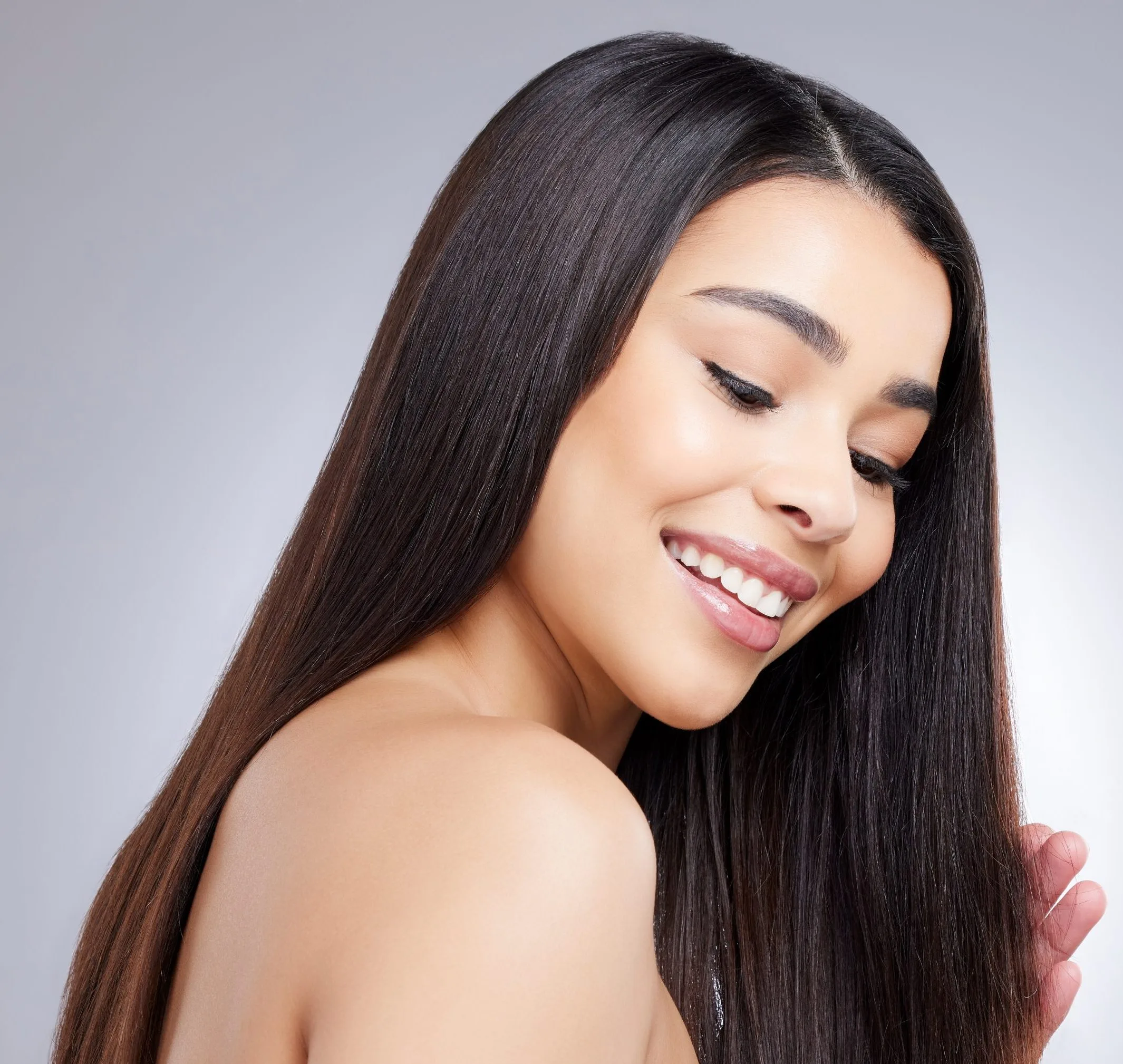 Woman with long dark hair smiling and looking over shoulder