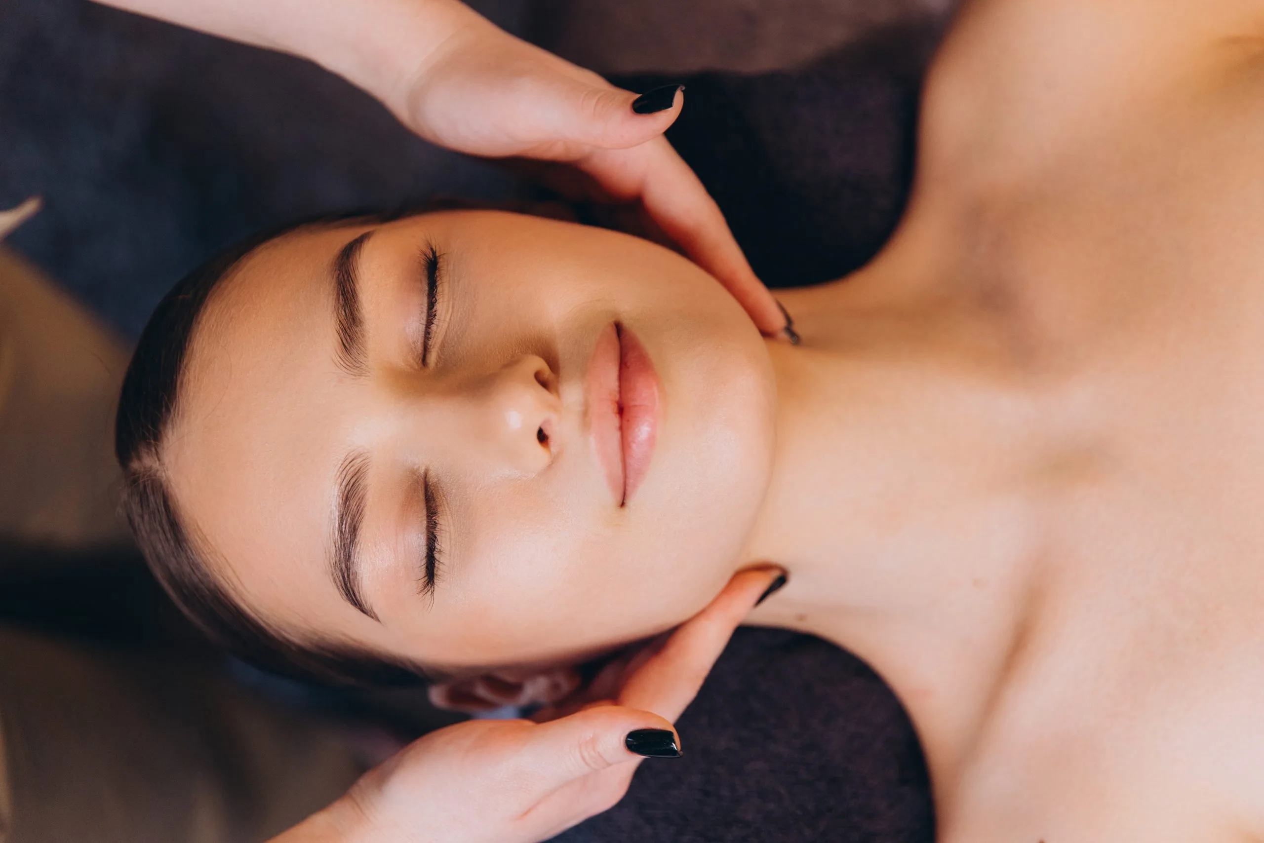 Practitioner applying skincare product to client's face during facial treatment