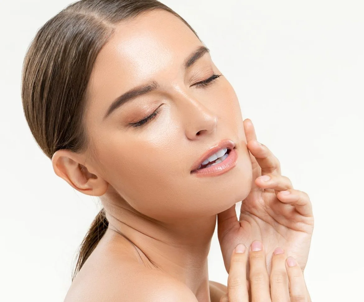 Woman with glowing skin touching her face and neck