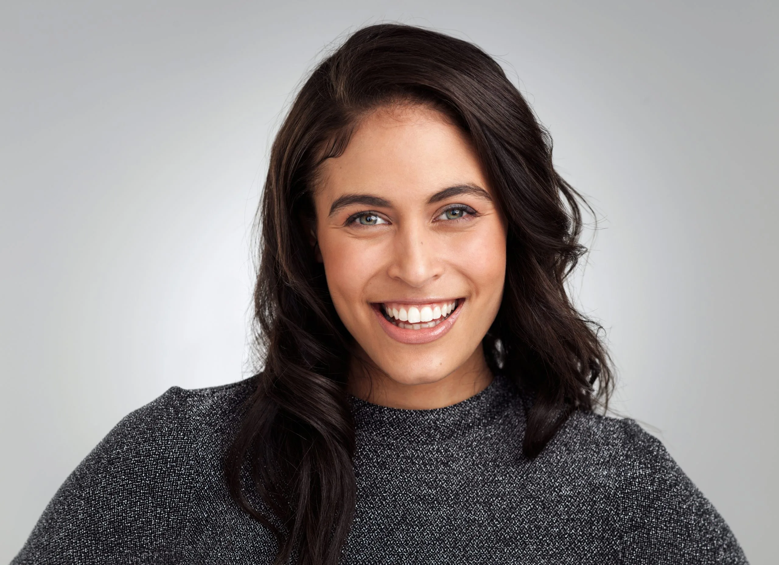 Woman with long dark hair smiling broadly at the camera
