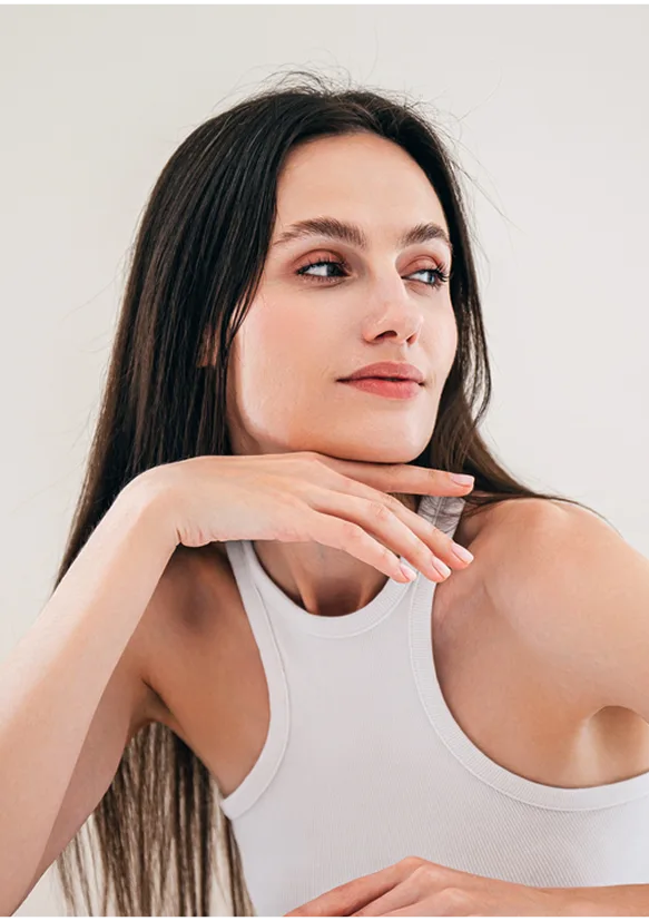 Woman with dark hair and red-toned eye makeup in white sleeveless top