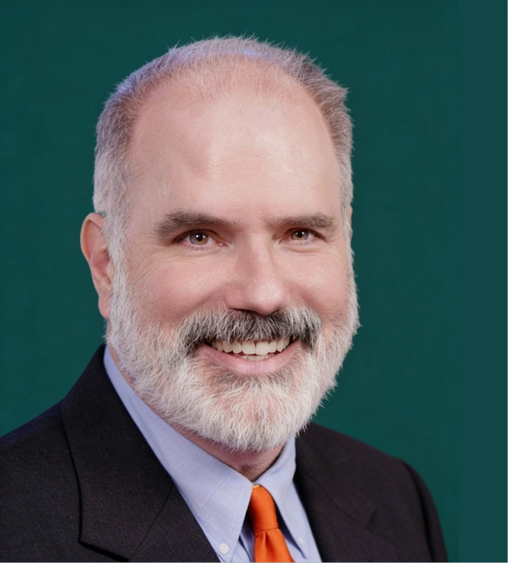 Stephen E. Metzinger, professional headshot wearing blue shirt and orange tie