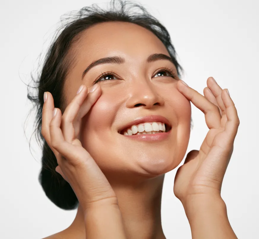 Woman with glowing skin smiling and touching her face after aesthetic treatment