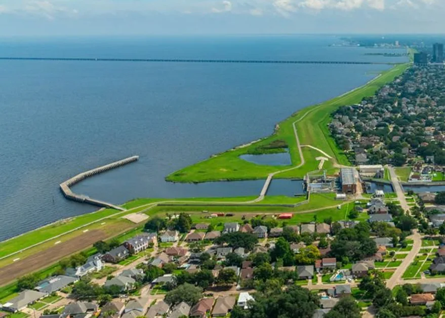 Aerial view of coastal landscape with green fields, waterway, and residential area