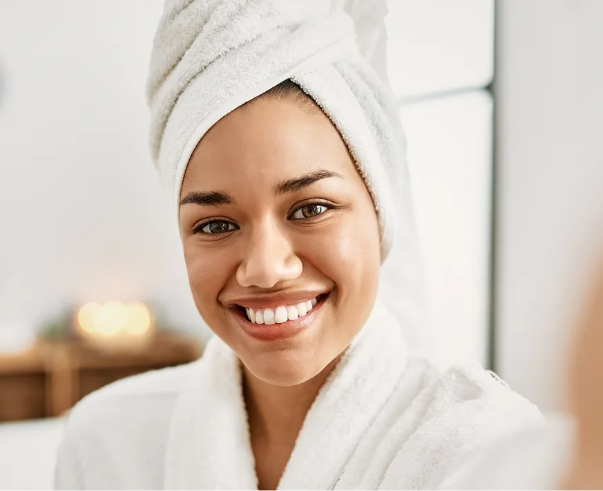 Smiling woman wearing white towel headwrap and robe in spa setting