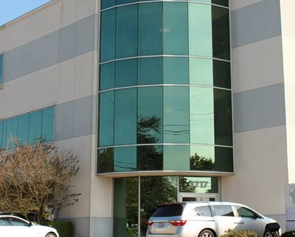 Modern medical office building exterior with curved glass windows and horizontal stone bands in Metairie