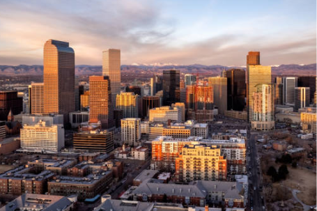 Denver skyline at sunset with downtown high-rise buildings and Rocky Mountains in the distance