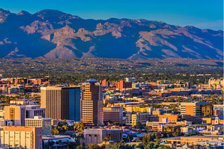 Tucson, Arizona cityscape with downtown buildings framed by desert mountains under blue sky