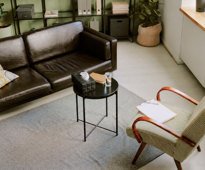 Modern psychiatric care office with leather sofa, round side table, and potted plants