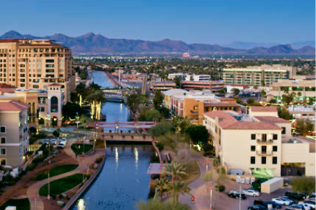Scottsdale, Arizona waterfront district with canal, palm trees, residential and office buildings, and mountains