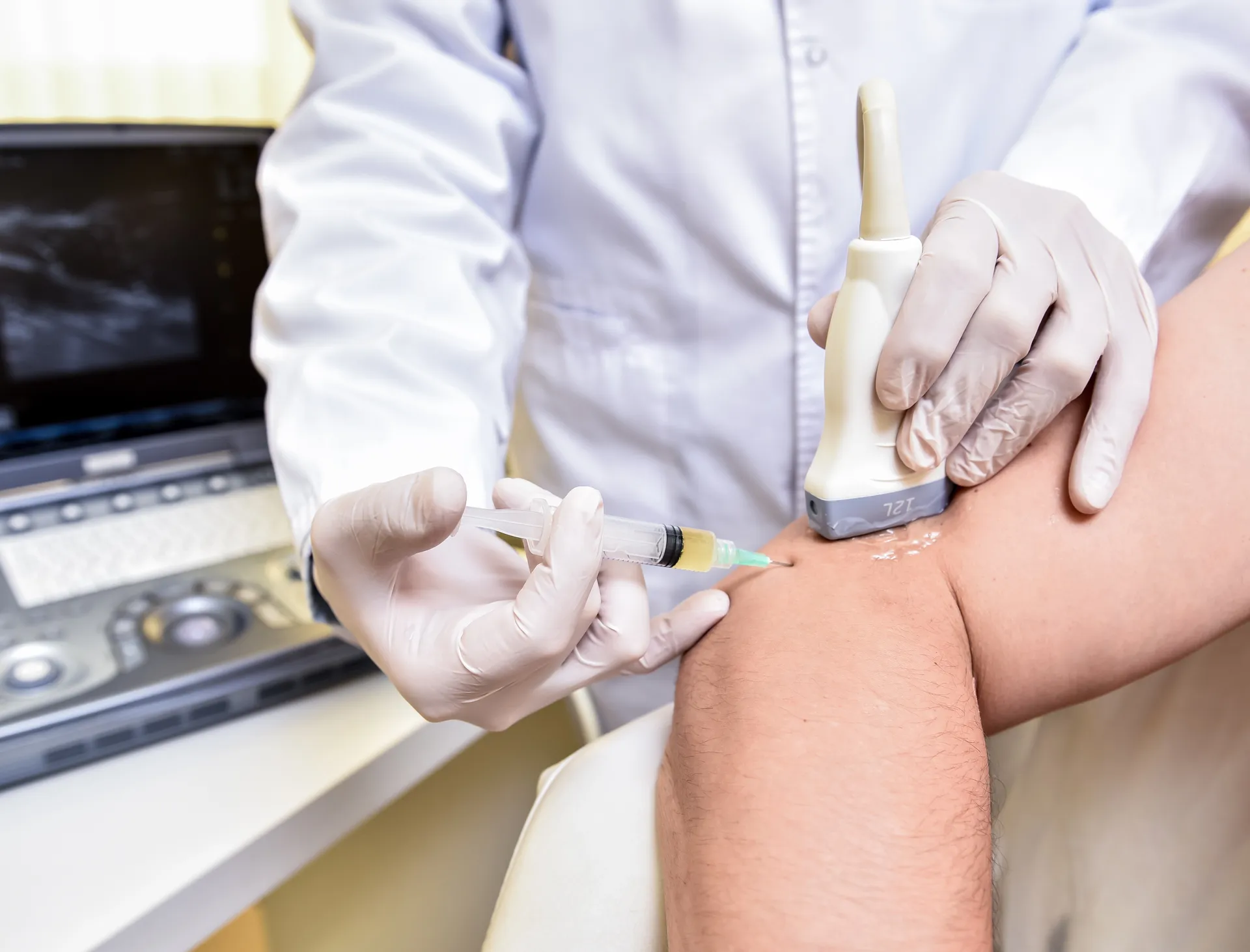 Close-up of a clinician performing an ultrasound-guided injection into a patient's knee for pain management.