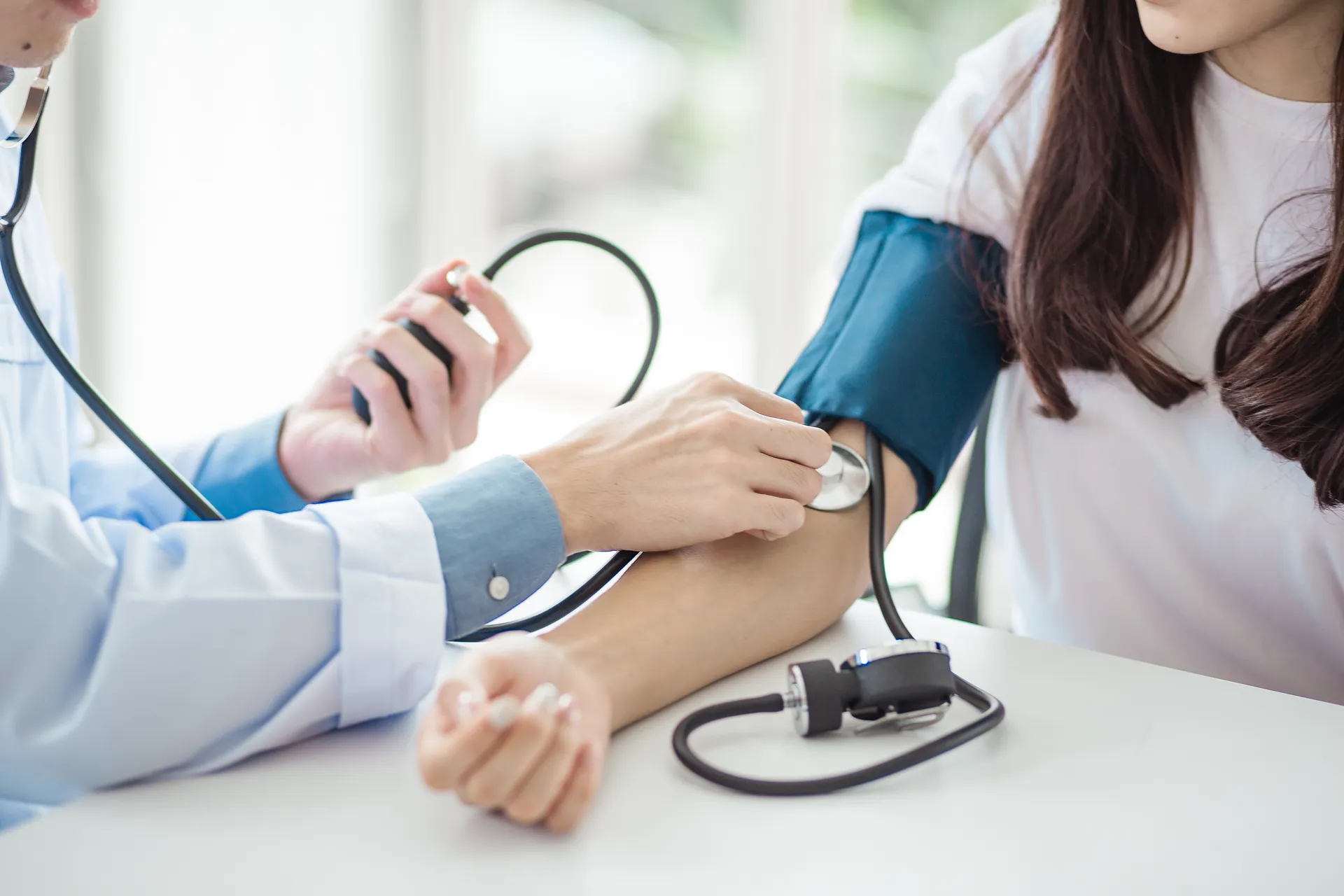 A doctor measures a patient's blood pressure using a cuff and stethoscope during a checkup.