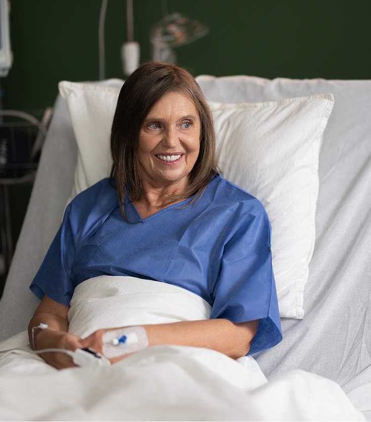 Patient in blue shirt sitting on hospital bed holding wound care device on arm