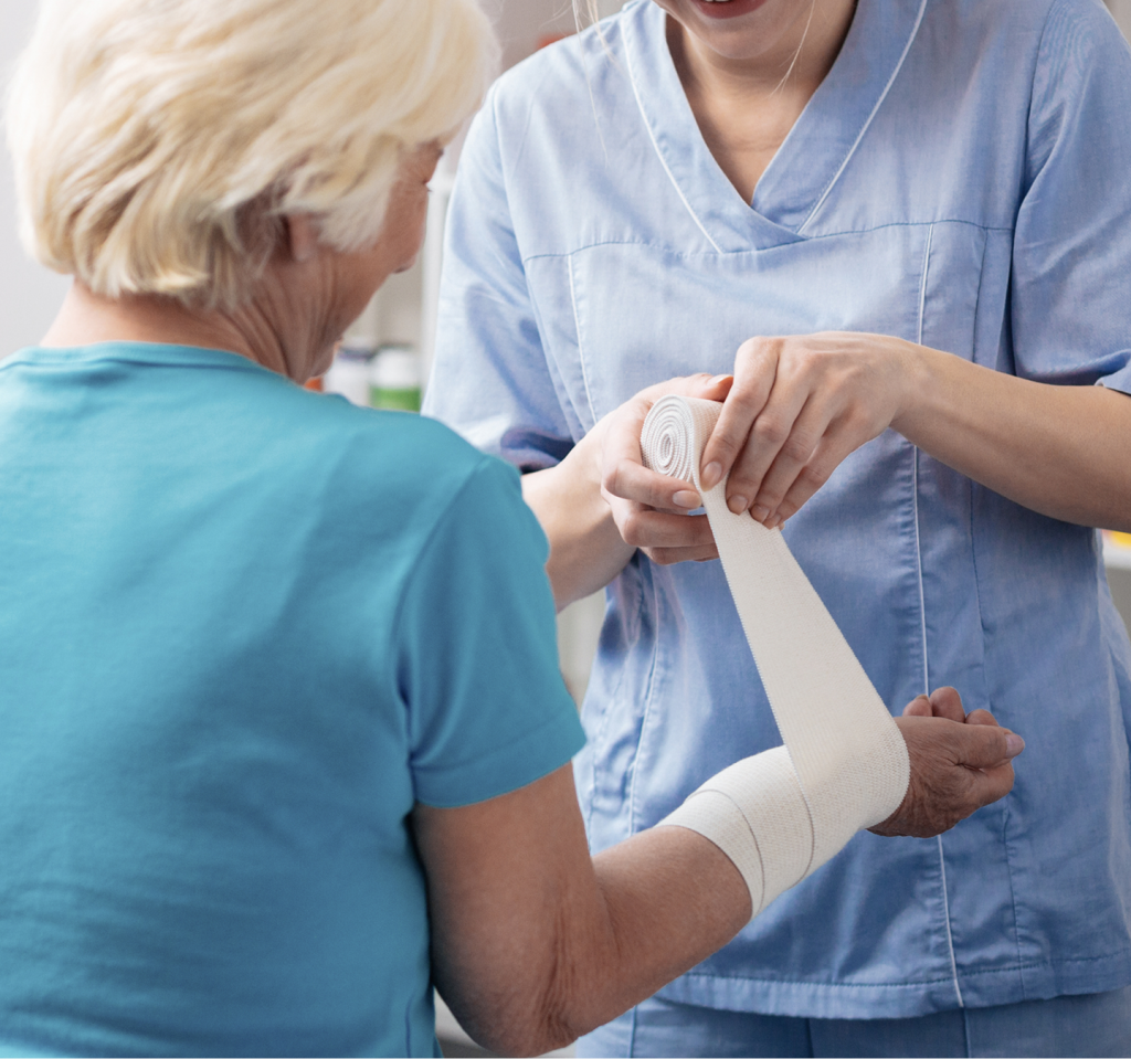 Healthcare provider wrapping white bandage around elderly patient's arm