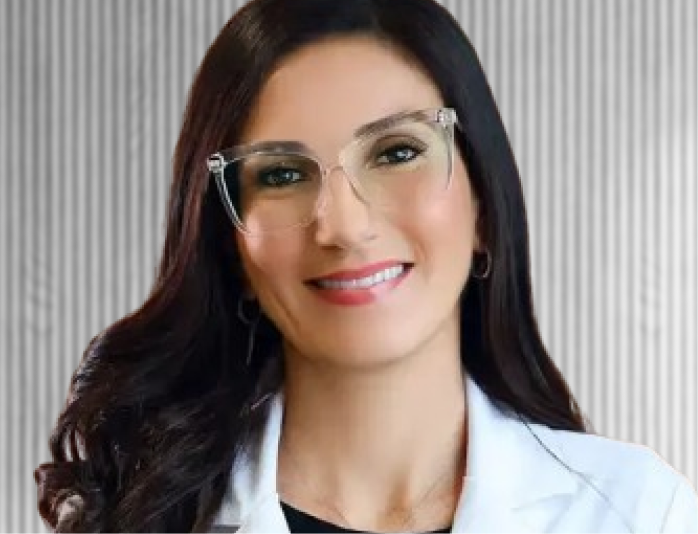 Professional headshot of Dr. Aisha wearing glasses and white coat