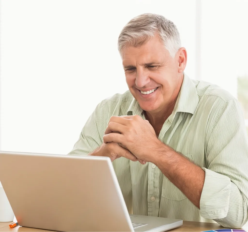 Man smiling while using laptop at desk