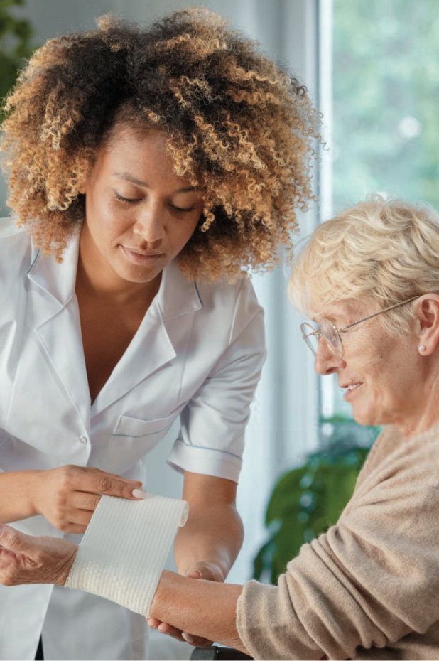 Healthcare provider in white coat wrapping bandage around senior patient's arm