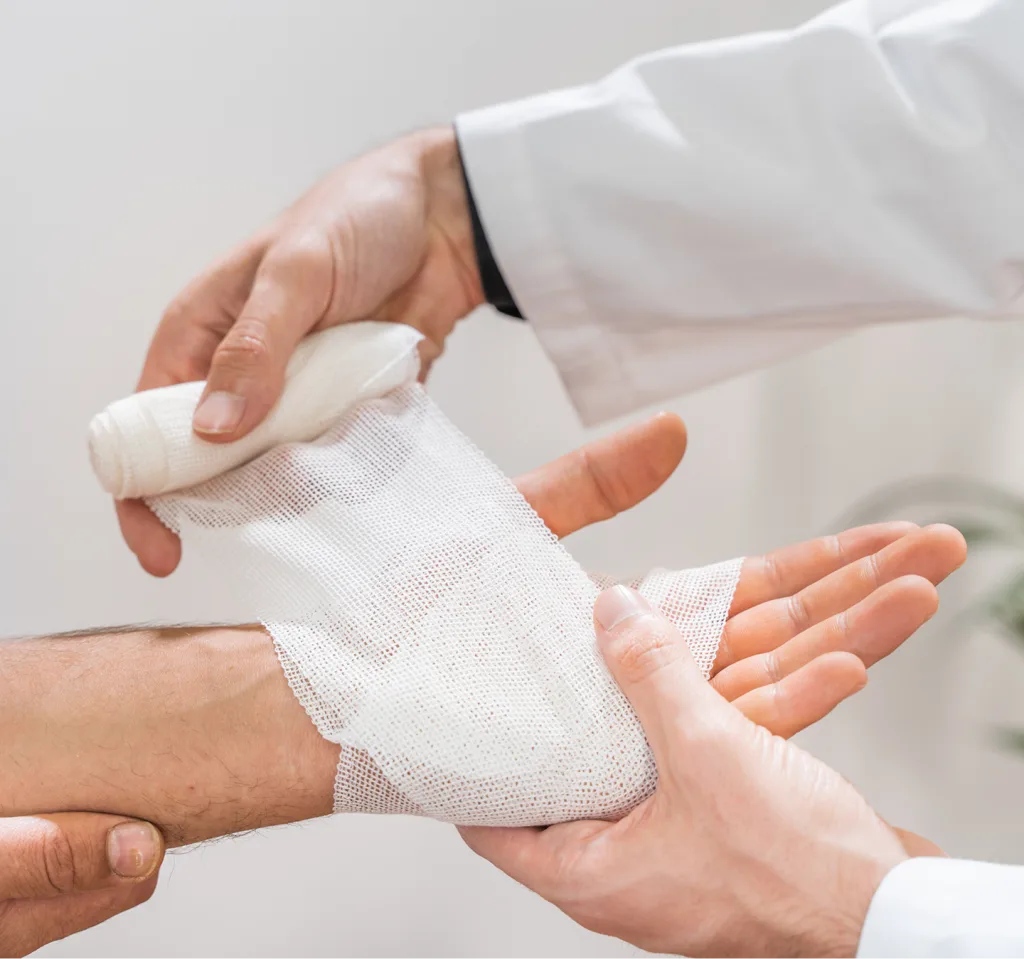 Healthcare provider wrapping a patient's hand with white gauze during wound care treatment