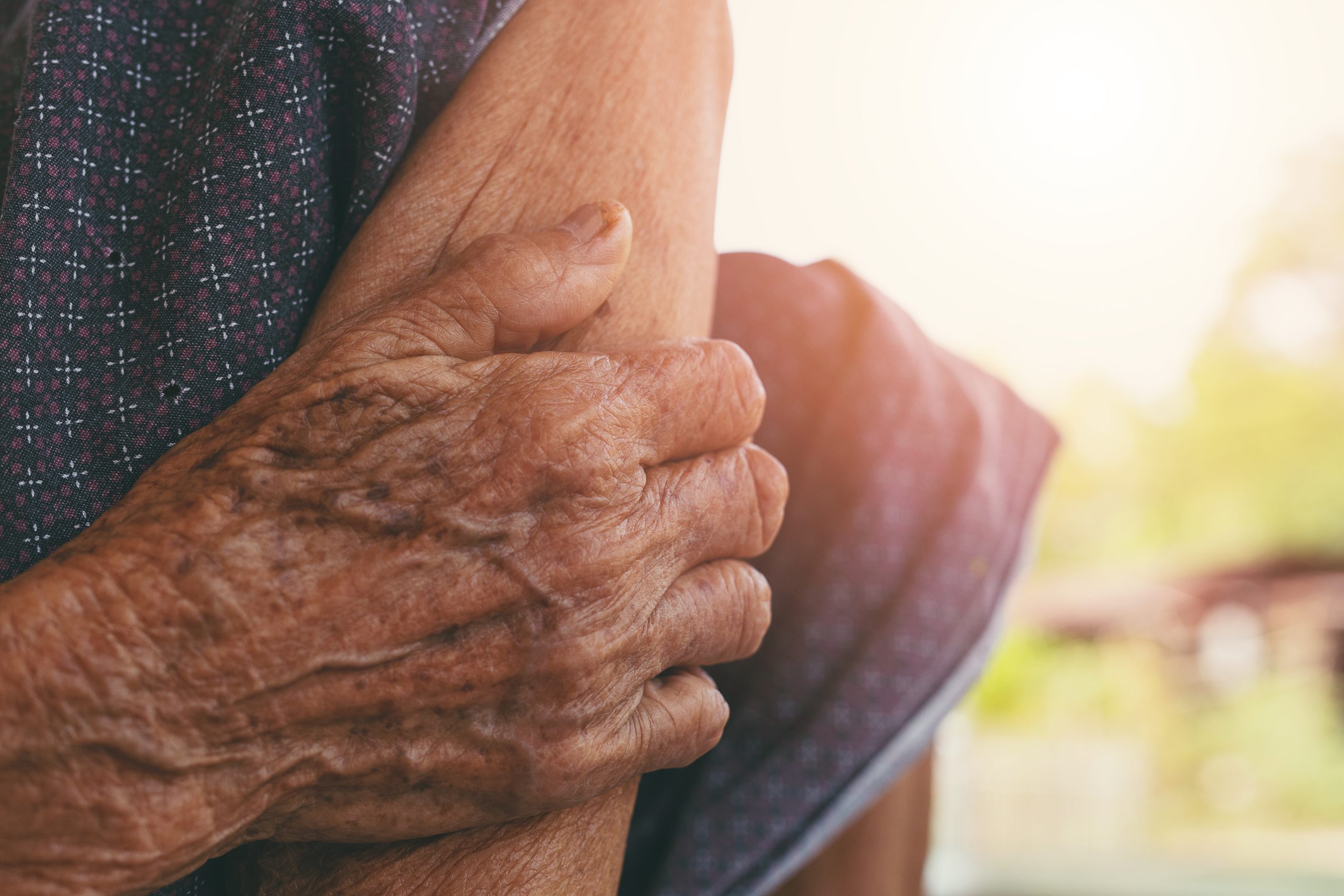 Older adult holding their arm, demonstrating muscle or arm pain