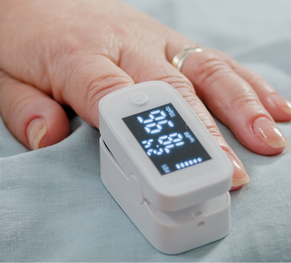 Pulse oximeter device on patient's finger displaying oxygen saturation reading