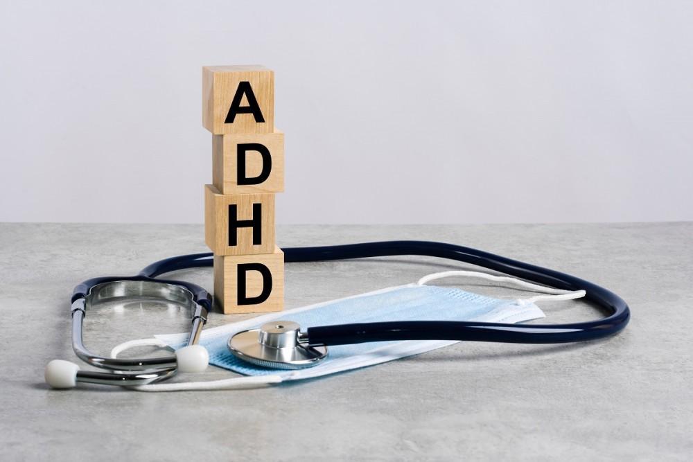 Wooden blocks spelling ADHD next to a stethoscope