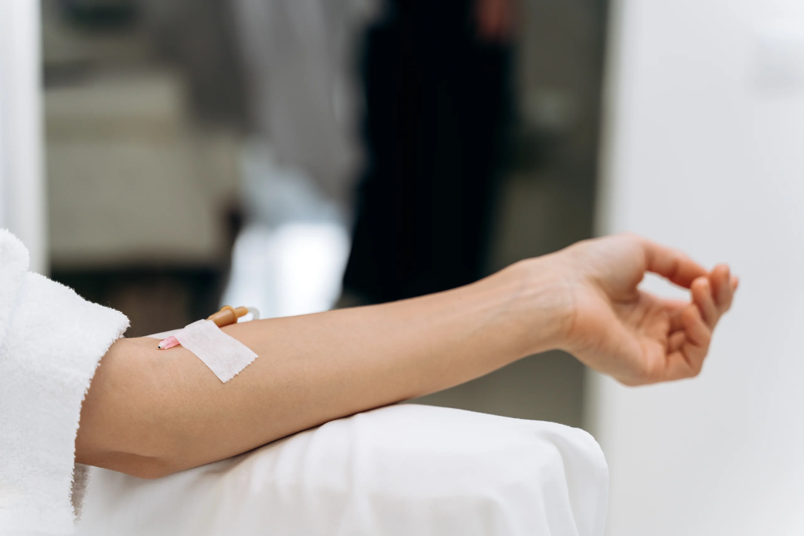 Close-up of a patient's arm with an IV line resting on a cushion