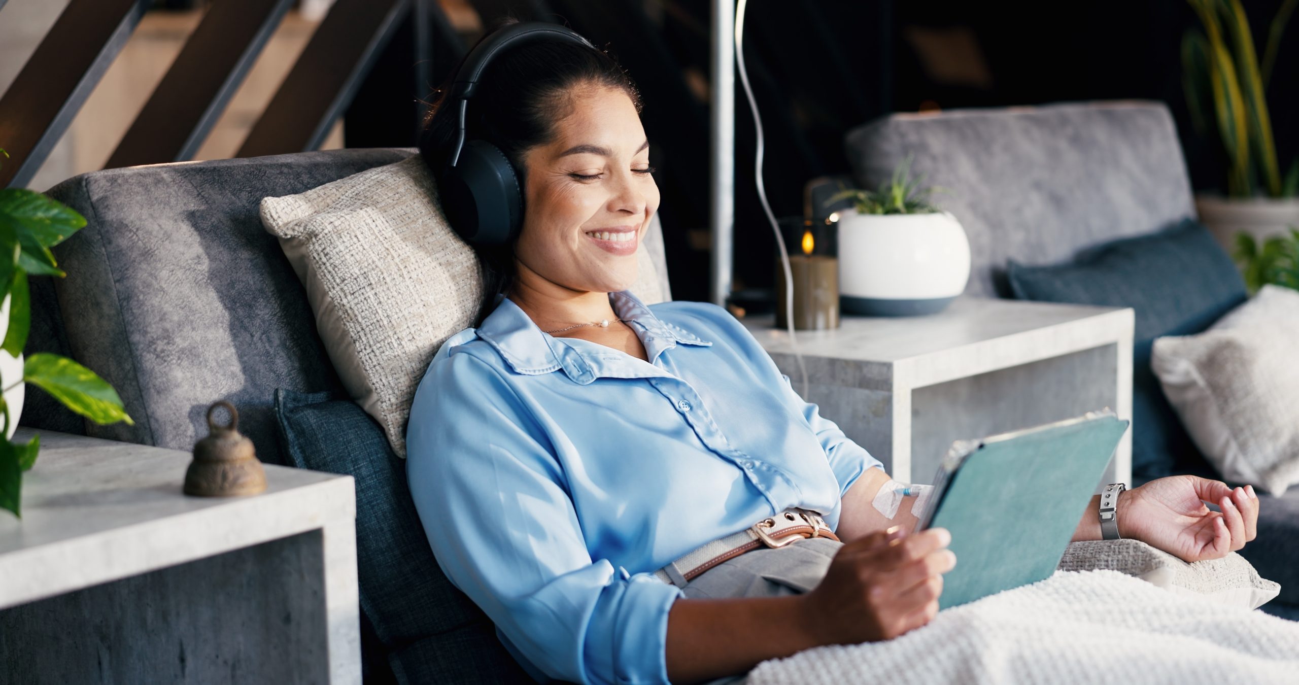 Woman with headphones and a tablet relaxing during an IV infusion