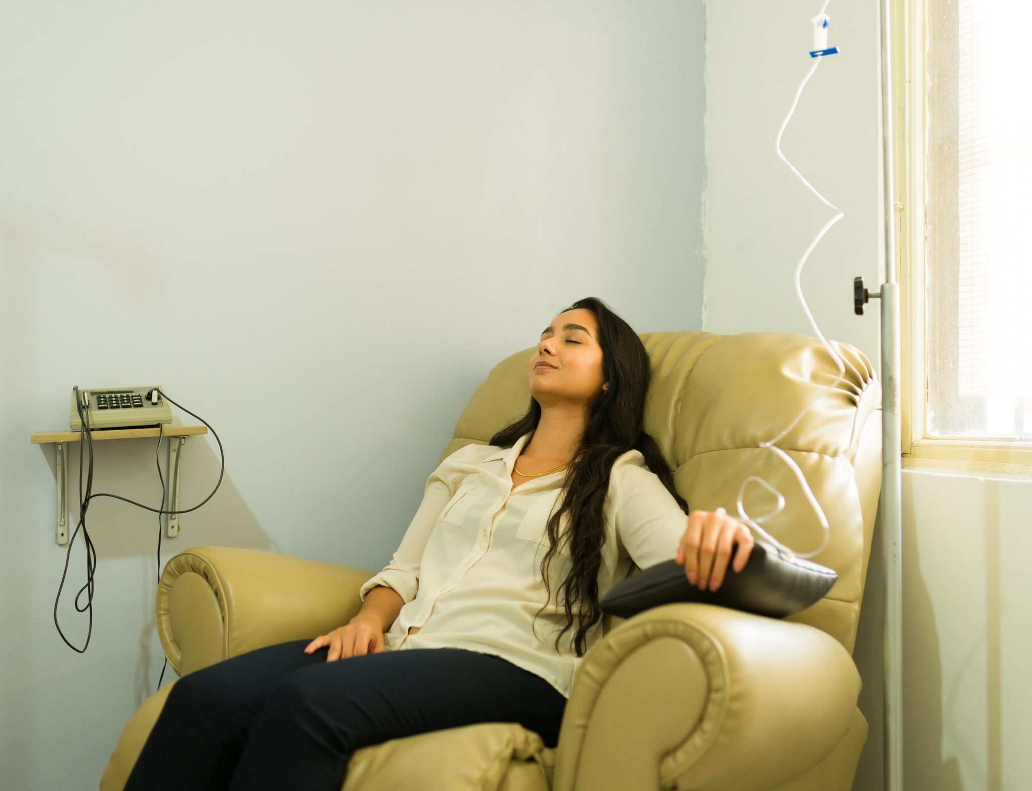 Woman resting with her eyes closed in a recliner during an IV infusion