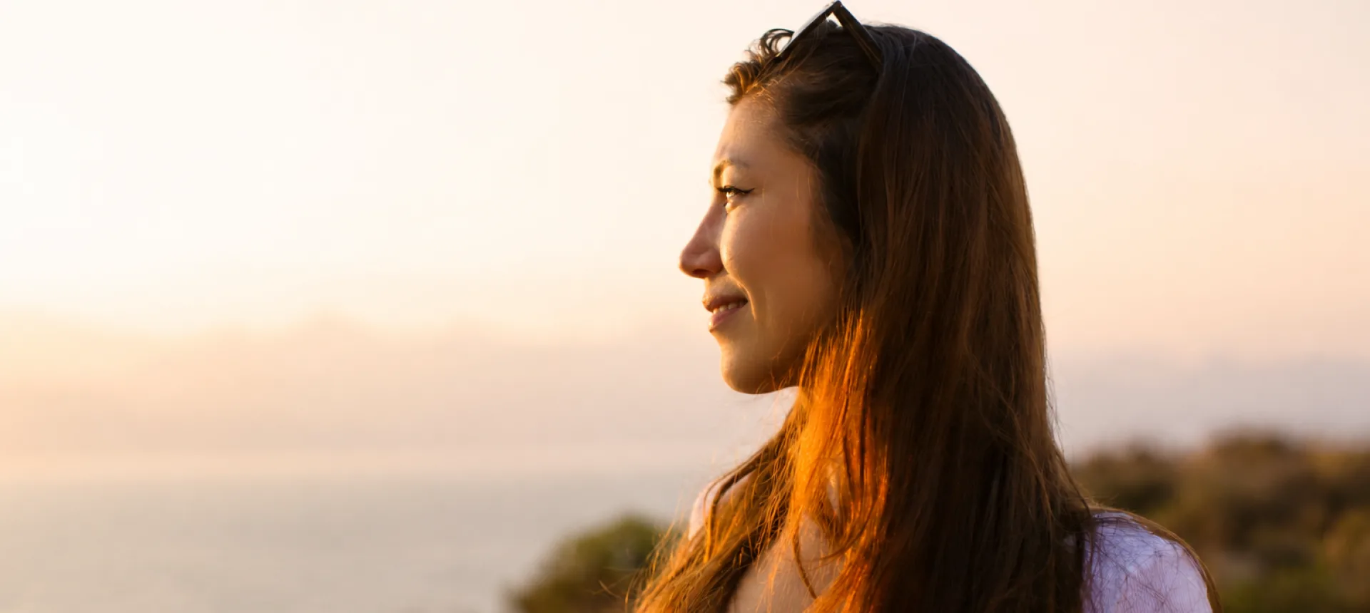 Woman looking calmly at the ocean at sunset