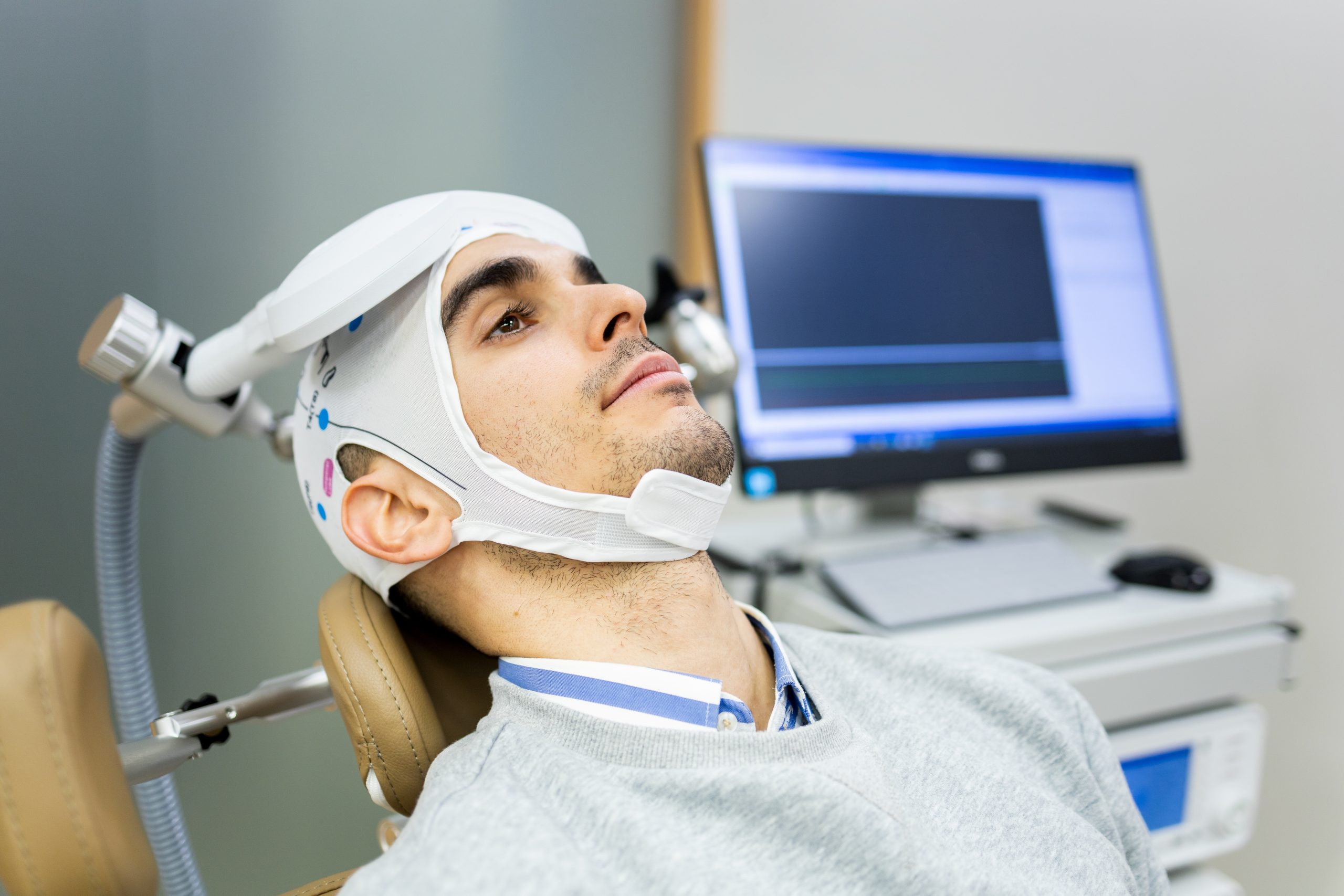 Young man in a treatment chair wearing a TMS cap during a session