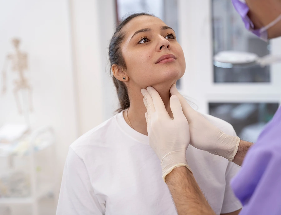 Doctor in gloved hands palpating patient's thyroid during clinical examination