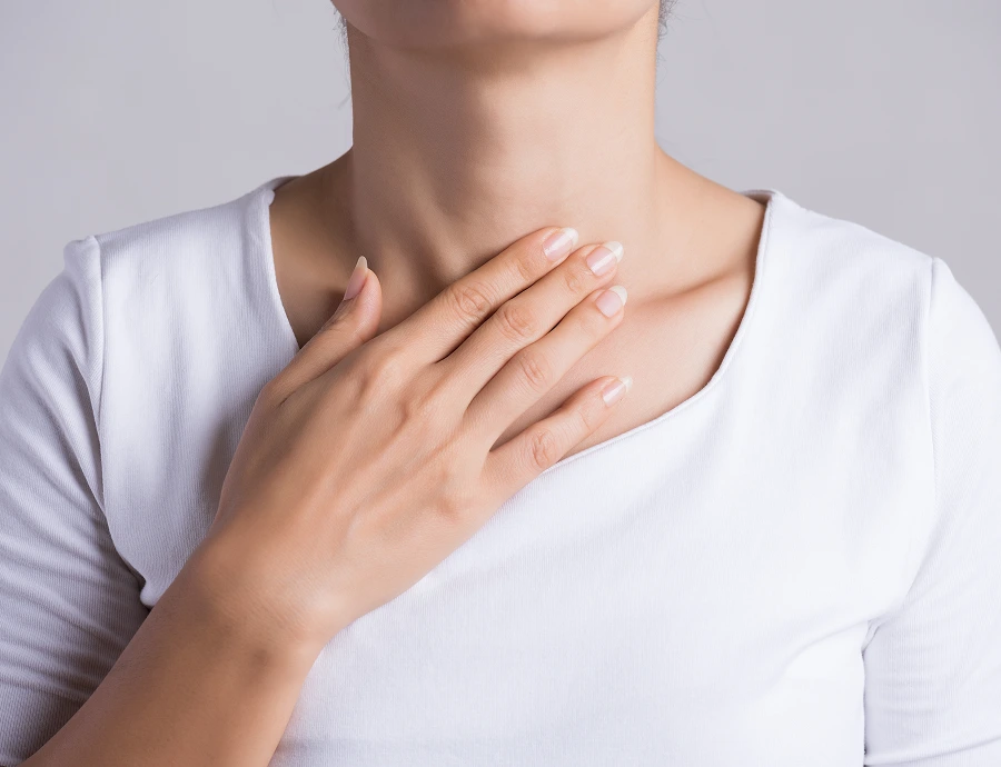 Woman in white shirt touching neck area with hand