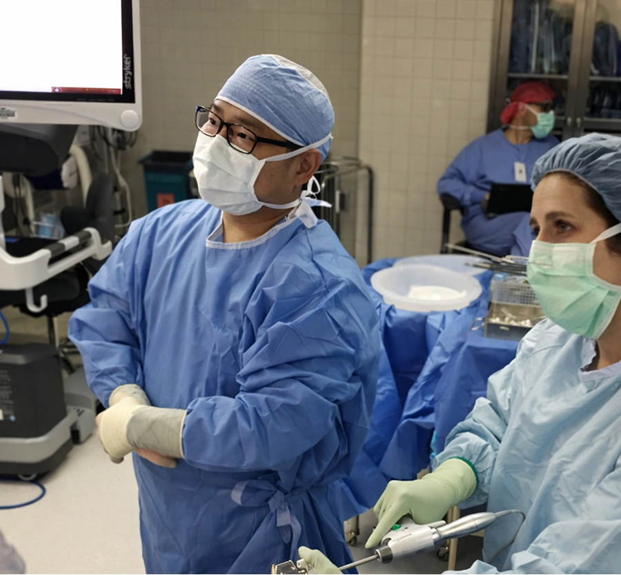 Surgeon in blue scrubs and mask performing parathyroidectomy with surgical team assisting