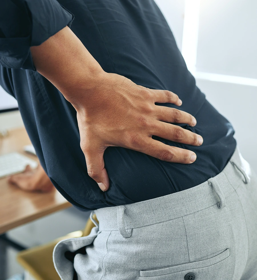Person holding abdomen with hands in discomfort while wearing dark shirt and gray pants