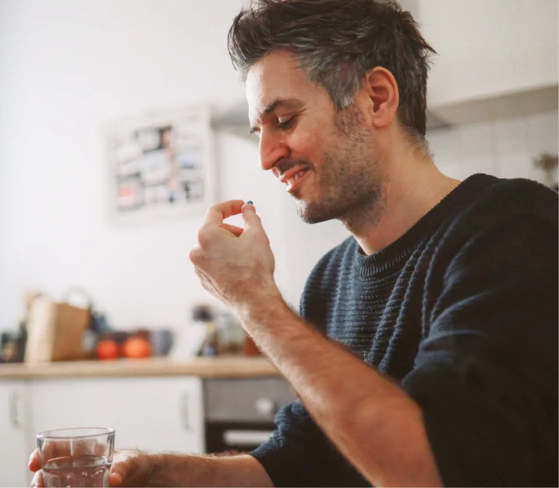 Man taking a medication with water in his kitchen
