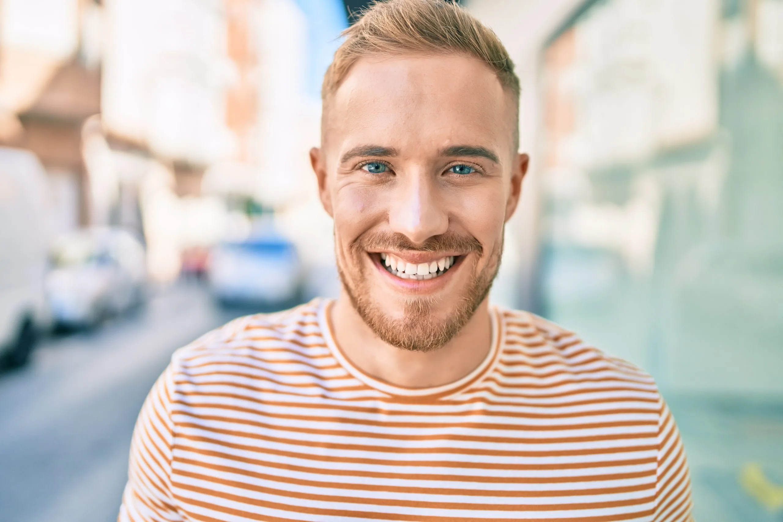 Smiling man in orange striped shirt on city street