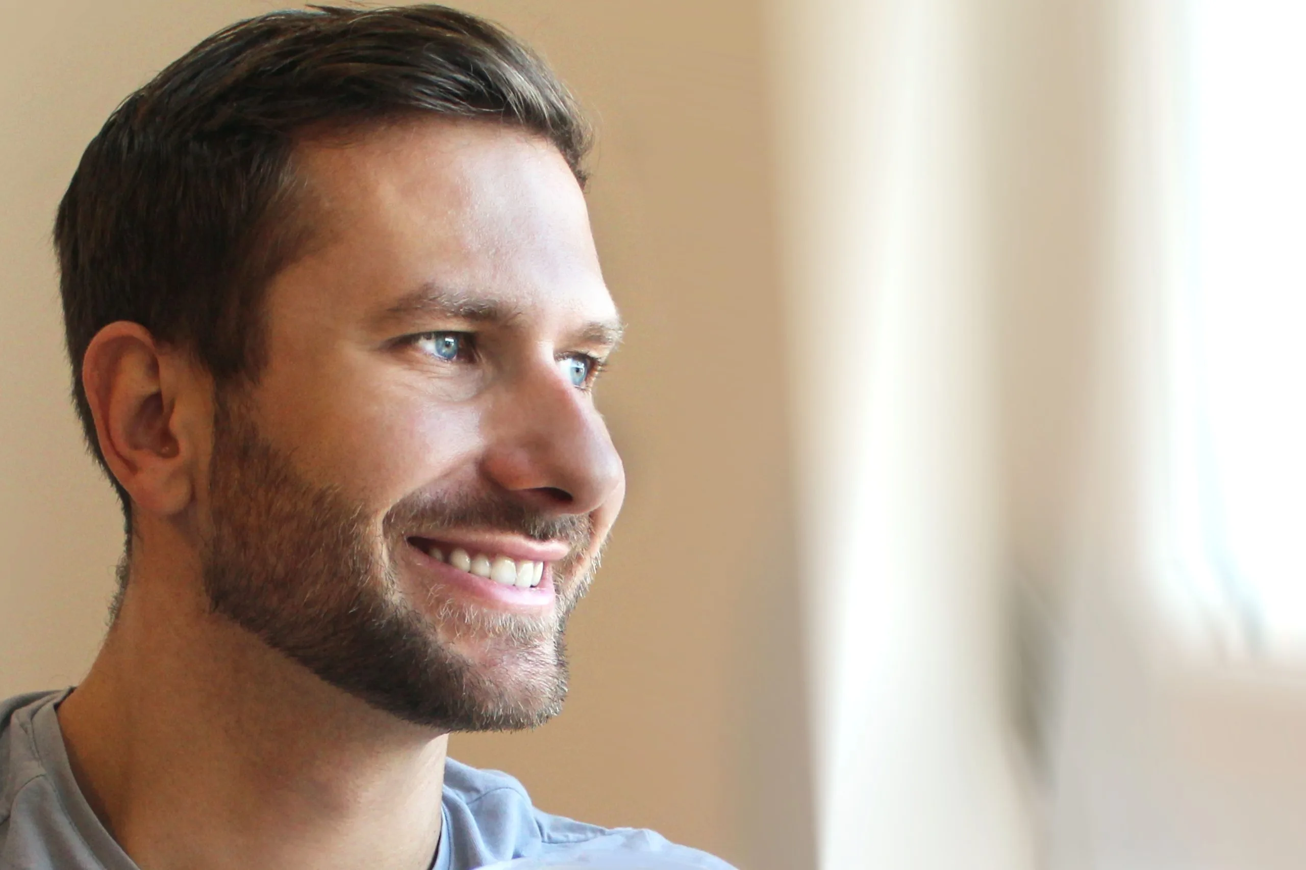 Profile view of smiling man with beard in light blue shirt