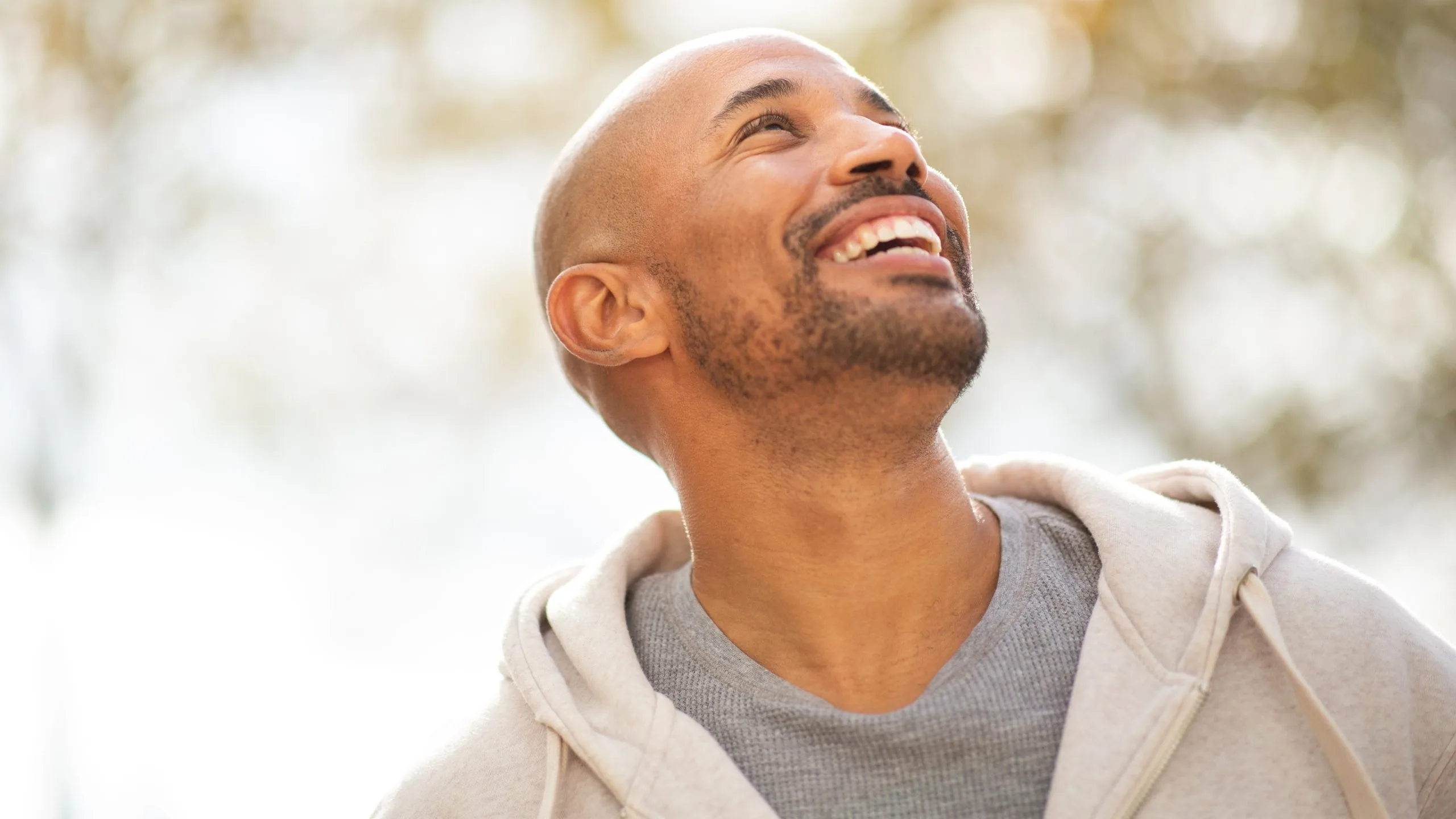 Man looking upward with joyful expression outdoors in natural lighting
