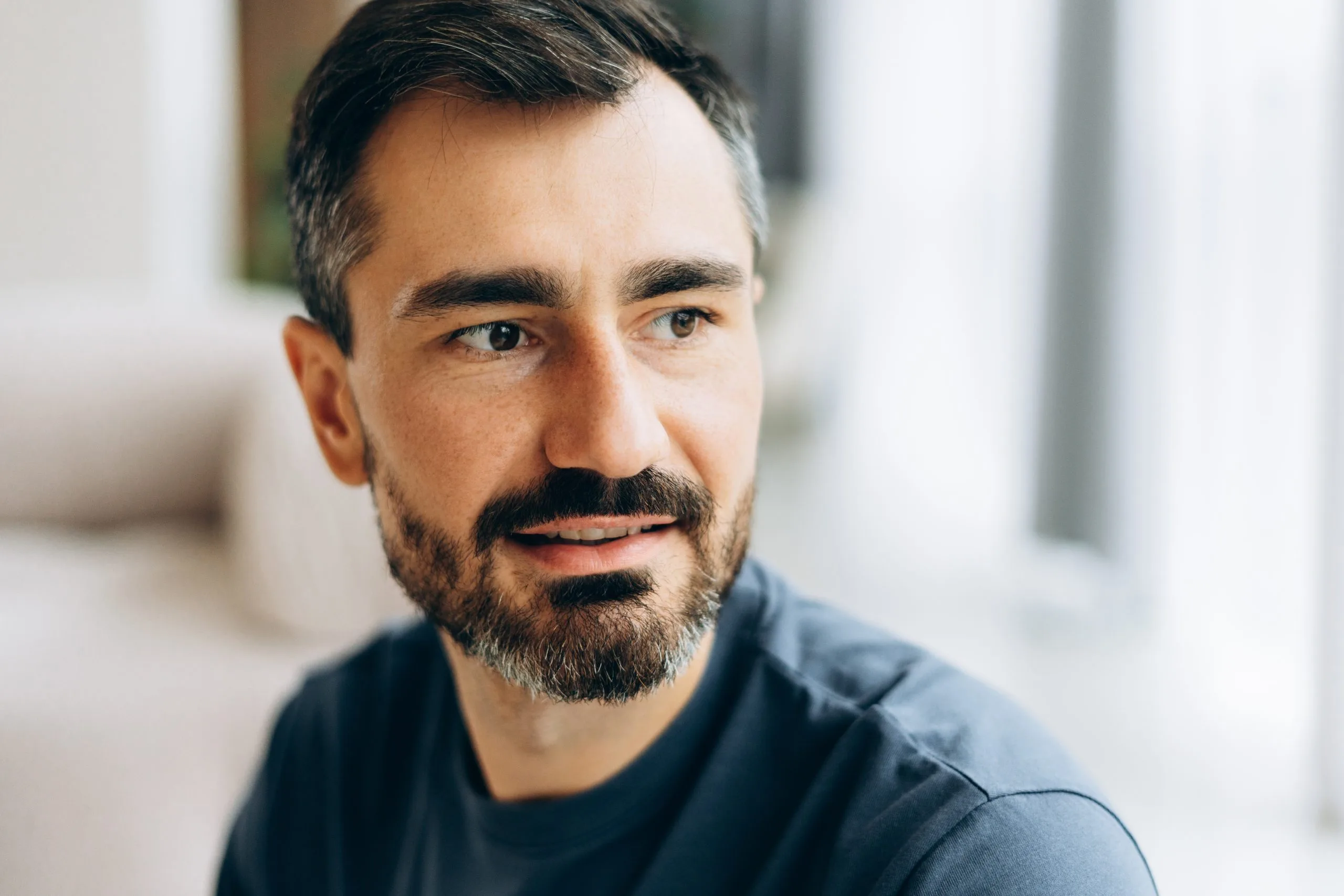 Man with beard smiling at camera in bright indoor setting