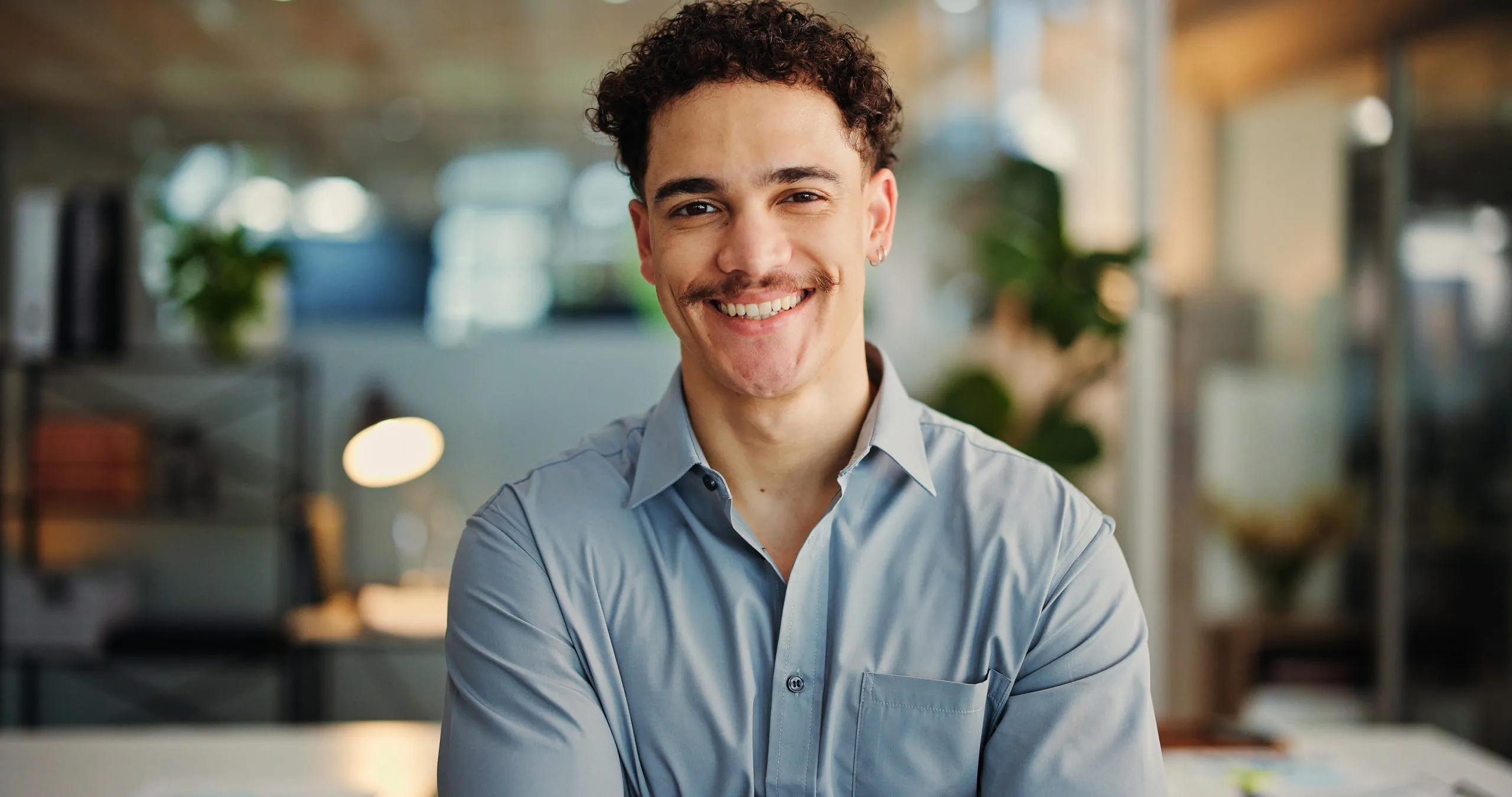 Smiling man in light blue button-up shirt in a modern office setting
